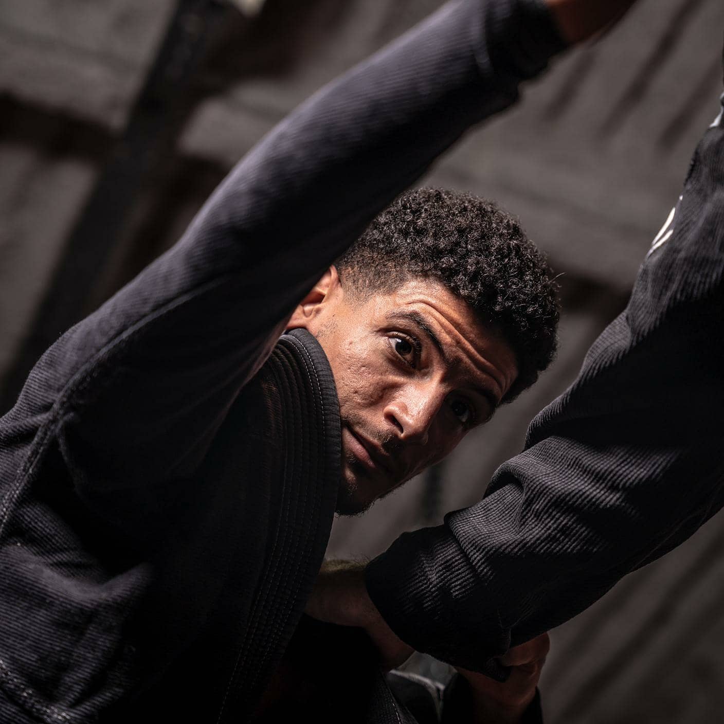 Younes, professeur principal, en kimono noir et ceinture noire, en action au sol.